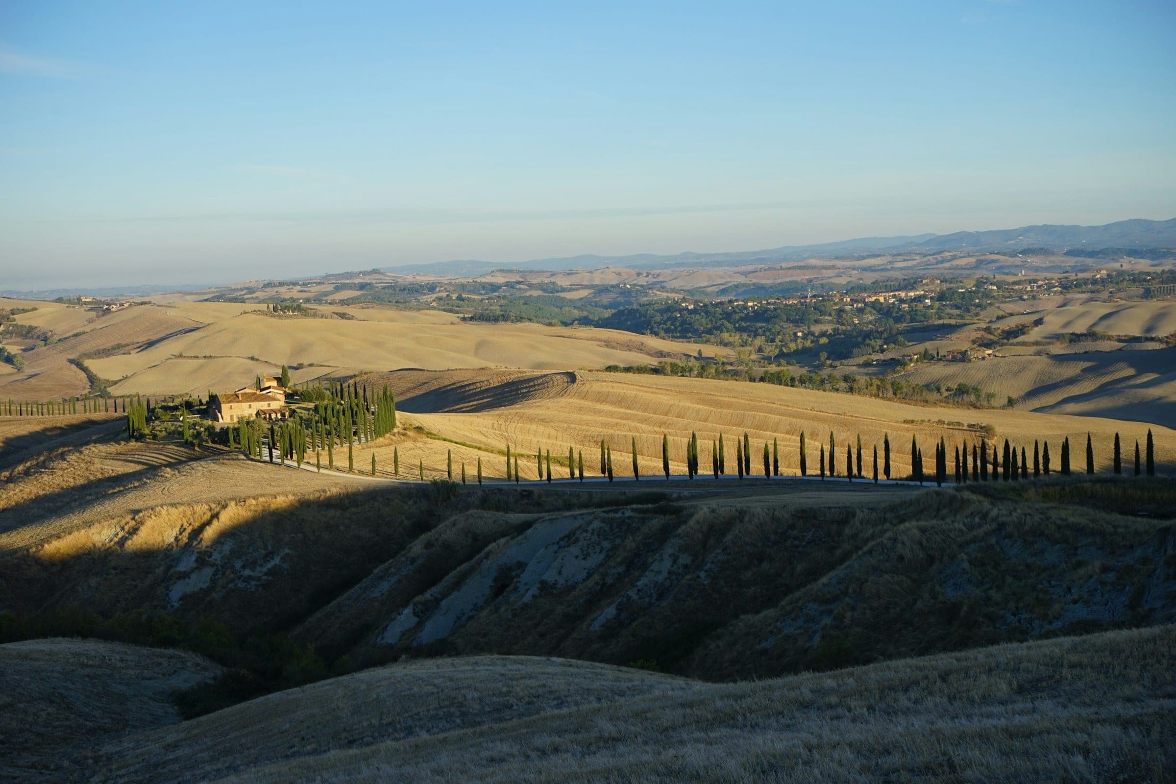 Tuscan hilltop with cypress trees above rolling golden countryside
