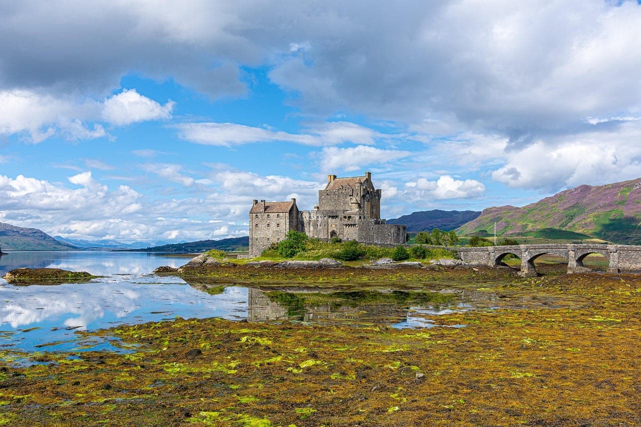 Eilean Donan Castle reflected in a still Highland loch beneath moody Scottish skies