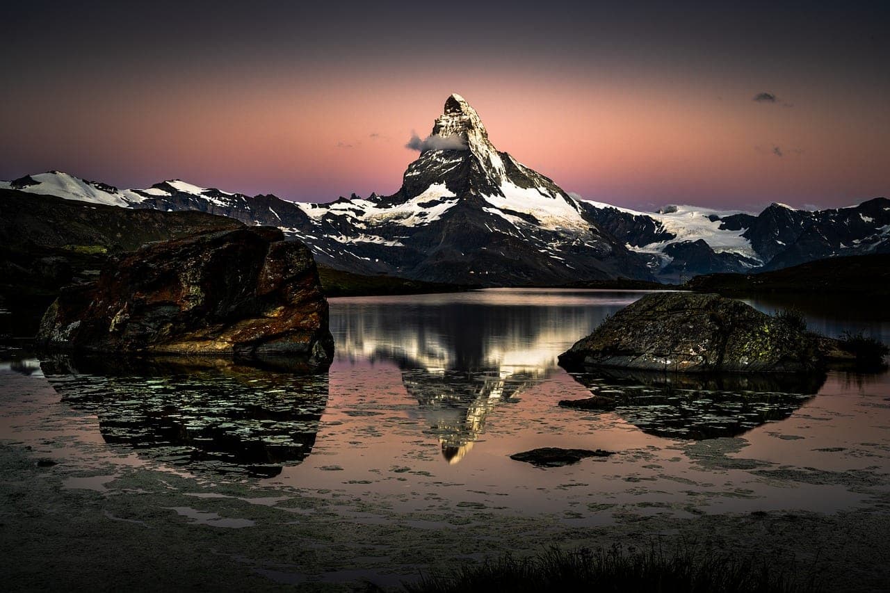 The Matterhorn mirrored in an alpine lake above a wildflower meadow in Switzerland