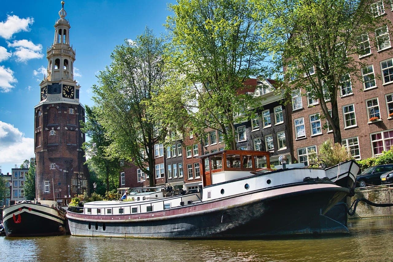 Gabled canal houses reflecting in an Amsterdam canal at golden hour