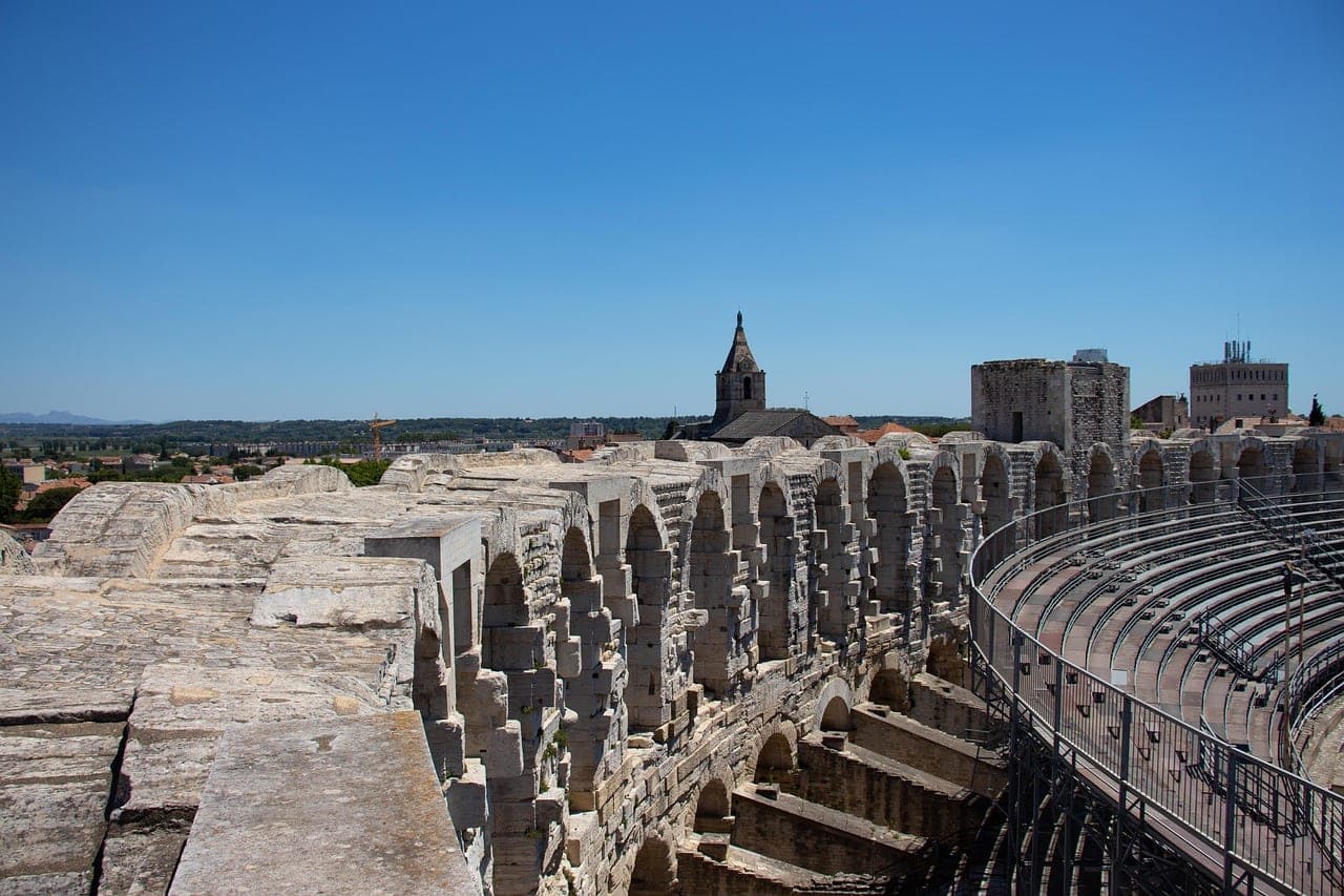 Roman amphitheater in Arles lit at dusk amid Provencal rooftops