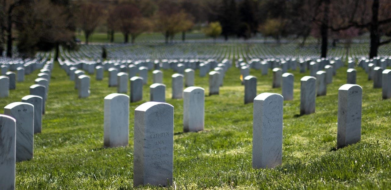 White marble headstones in rows at Arlington National Cemetery under autumn trees