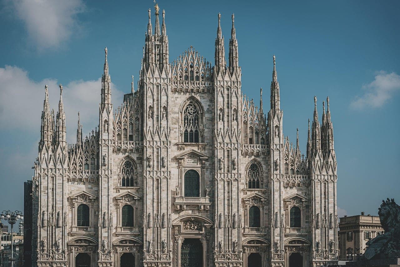 Milan Duomo cathedral facade with Gothic spires under blue sky in Piazza del Duomo