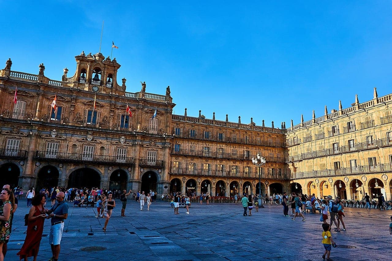The honey-colored sandstone arcades of Plaza Mayor in Salamanca, Spain, glowing at sunset
