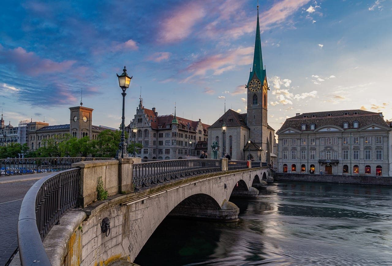 Grossmünster towers above the Limmat River in Zurich's old town with Lake Zurich beyond