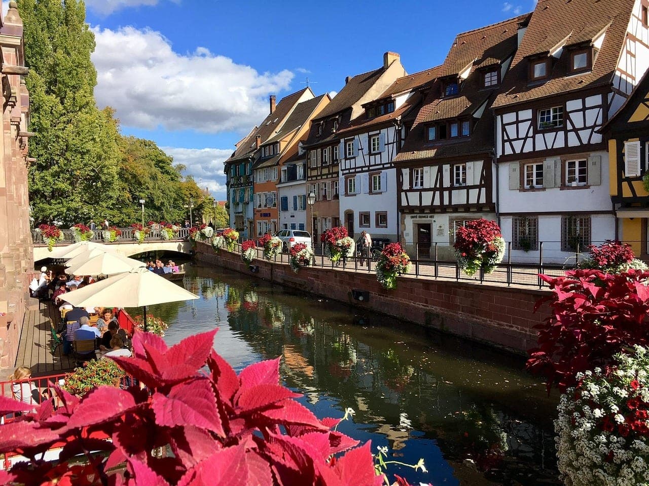 Flower-draped half-timbered houses reflected in the canals of old Colmar, Alsace